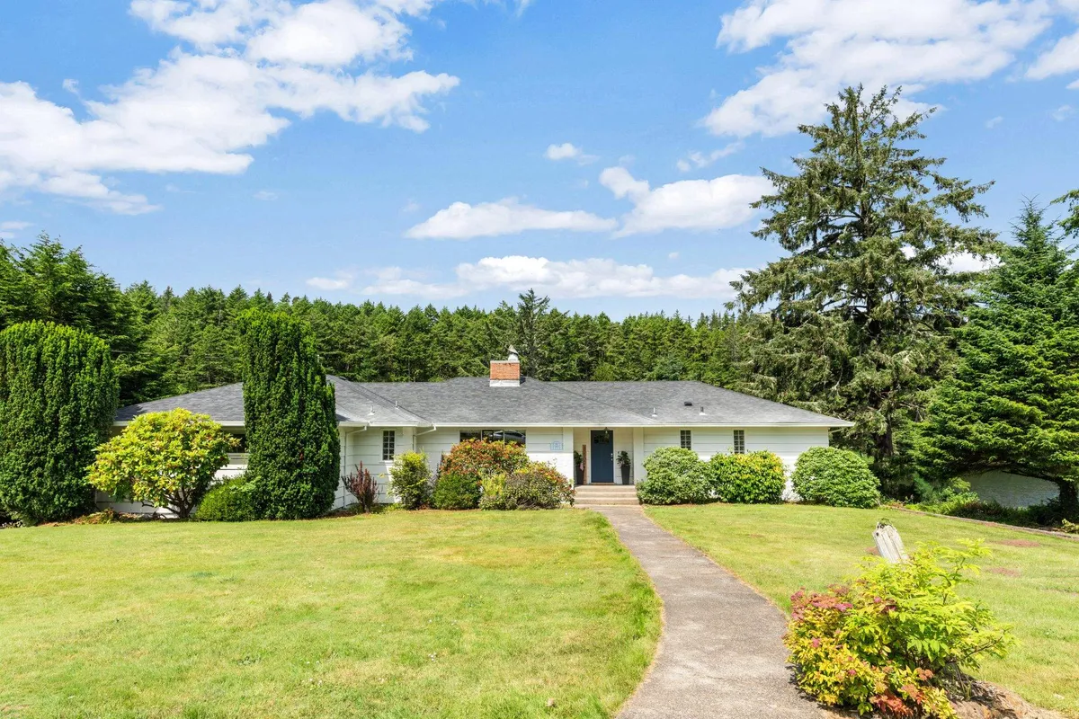 The home's front entrance is framed by a landscaped garden and large trees, with plenty of open space. This inviting exterior highlights the property's welcoming nature and emphasizes the spacious grounds available for both guests and pets.