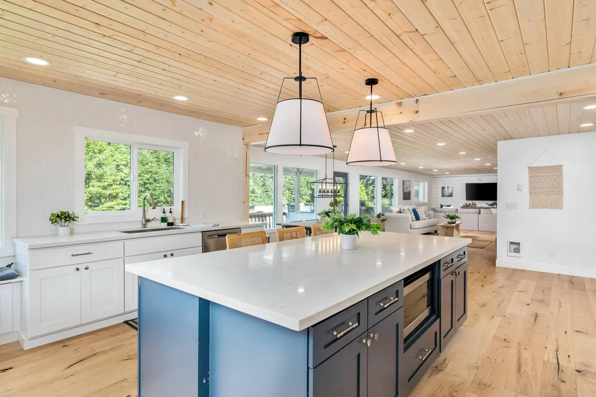 A large, welcoming kitchen highlighted by a spacious island, modern pendant lighting, and expansive windows that bring in plenty of natural light. The kitchen is designed for cooking, family gatherings, and entertaining guests, emphasizing communal meal preparation and enjoyment.